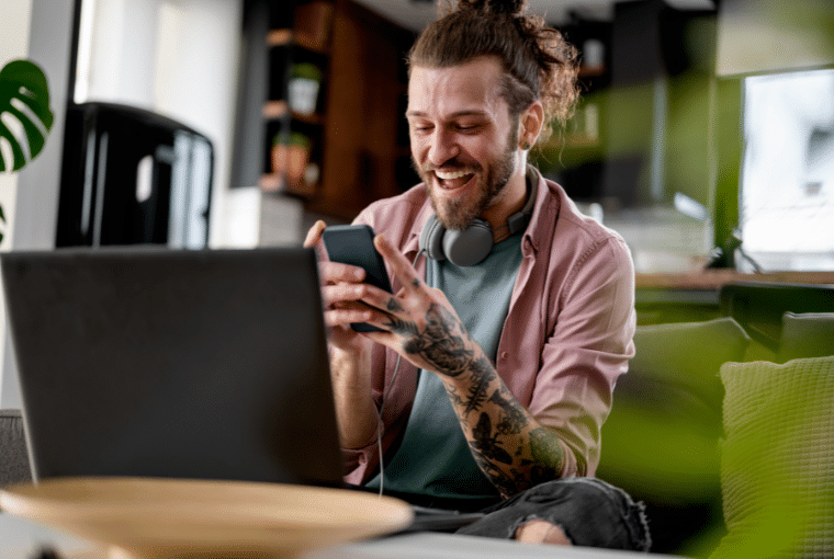A tattooed man smiles as he looks at his mobile