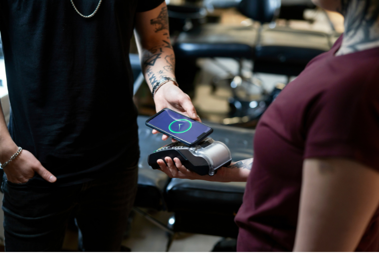 Tattoo artists accepts a card payment from a client with a card reader