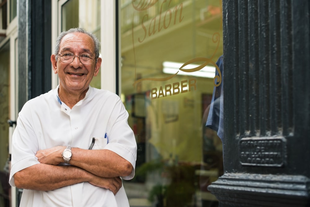 Man standing in front of his hair cutting business.