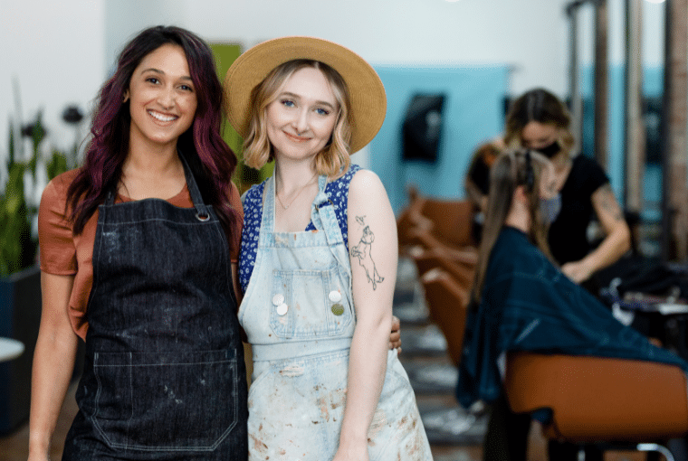 Two happy stylists take a break to pose for a photo in their salon