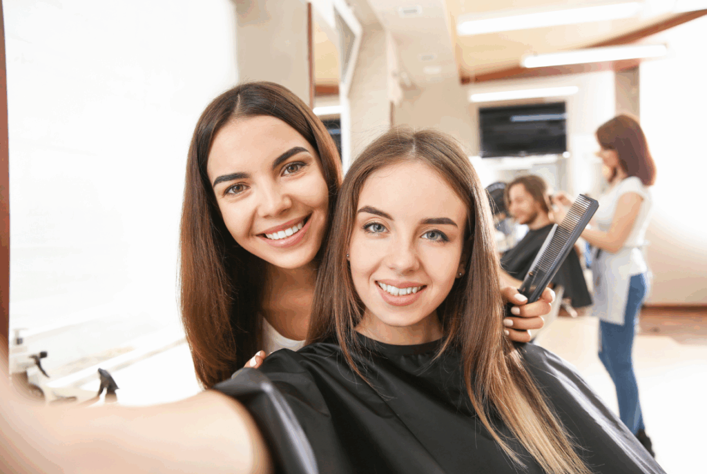 A young woman poses with her stylist mid-cut at the salon