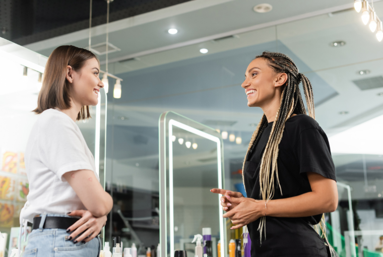 A smiling hairdresser chats warmly with a young customer about what she should have done at the salon today.