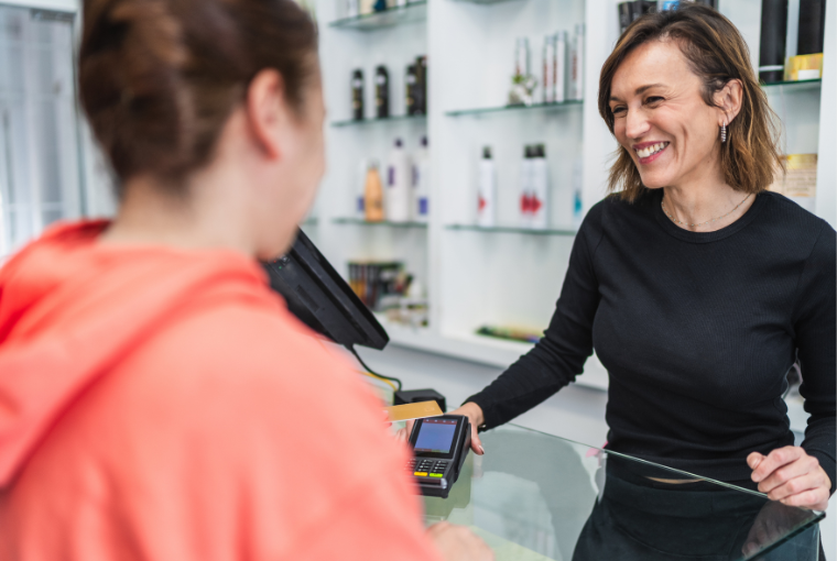 Smiling salon owner takes a payment from a client using a POS