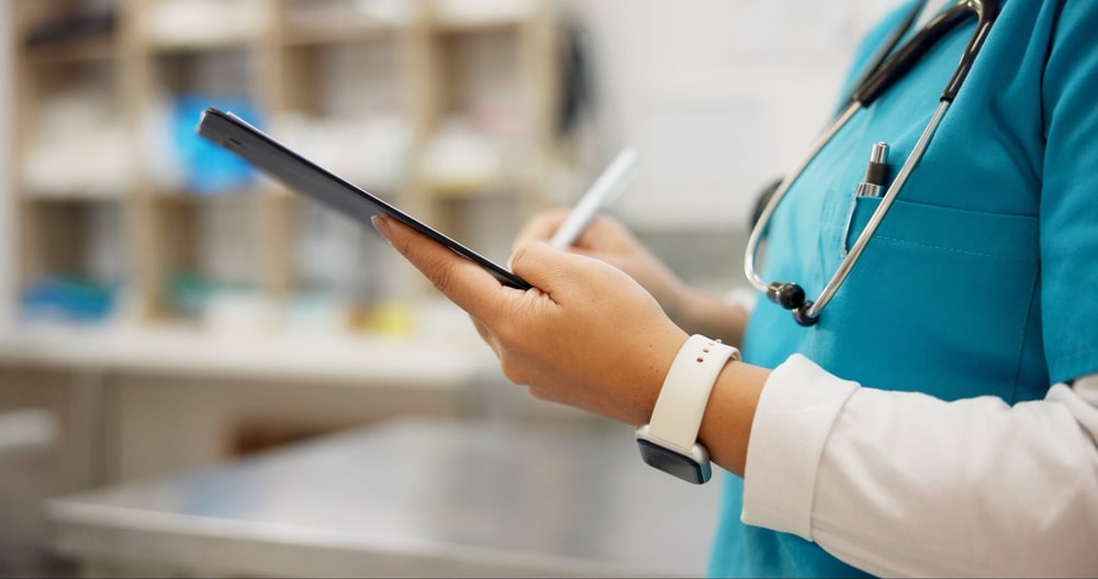 A female veterinarian uses a tablet to take notes during an exam.