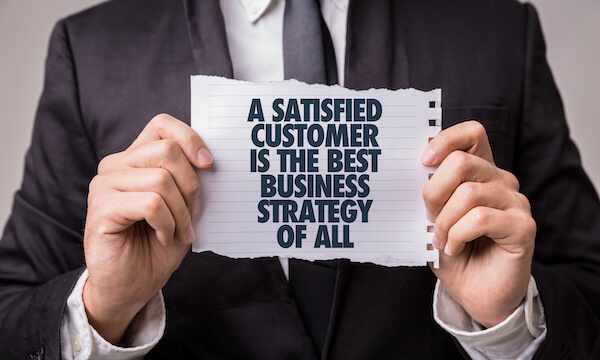 Person holding a torn note saying A satisfied customer is the best business stratgey of all